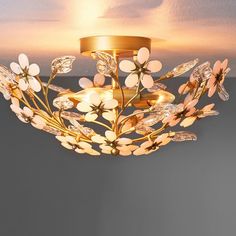 a chandelier with flowers and leaves hanging from it's ceiling light fixture