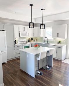 a kitchen with white cabinets and an island in the middle, surrounded by wood flooring