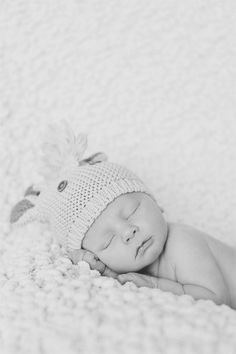 a black and white photo of a baby sleeping on a blanket with a stuffed animal