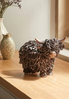 a cow figurine sitting on top of a wooden table next to vases