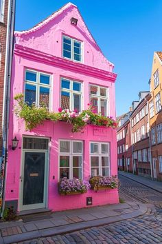 a pink house with flowers on the windows