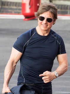 a man in sunglasses is running on the street with his arm wrapped around his waist