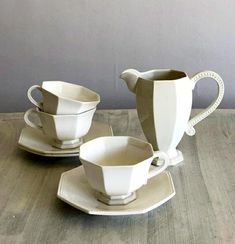 two white cups and saucers sitting on top of a wooden table