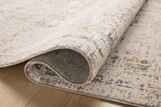 an area rug on the ground with a wooden floor in front of it and a light colored background