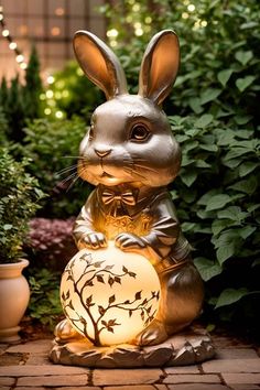 a statue of a rabbit sitting on top of a stone floor next to plants and potted trees