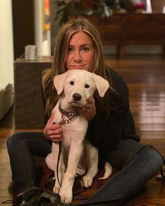 a woman sitting on the floor holding a white dog