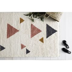 a white rug with black, pink and gold triangles on it next to slippers