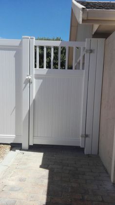 a white gate and brick walkway in front of a house