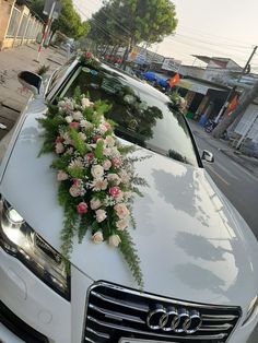 a car decorated with flowers and greenery on the hood