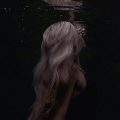 a woman with long blonde hair standing in the water