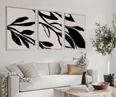 three black and white paintings hang on the wall above a couch in a living room