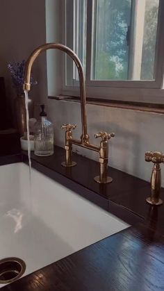 a bathroom sink with two faucets and a window in the backround