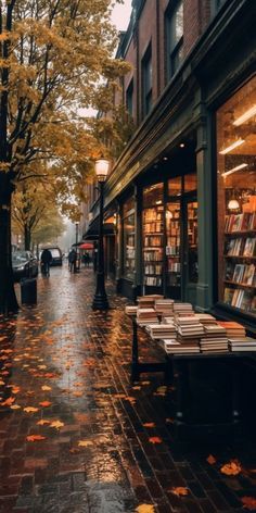 an empty street with books on the tables and people walking down the sidewalk in the rain