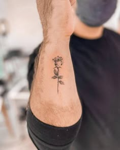 a man with a small rose tattoo on his left arm and wrist, holding up the camera