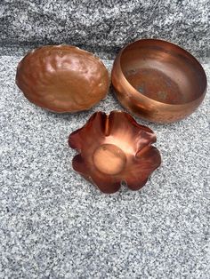 three metal bowls sitting next to each other on a stone surface with one bowl in the middle