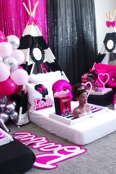 pink and black party decorations with barbie dolls on the bed, teepee tent in background