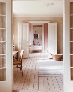 an open door leading into a room with white walls and wood flooring on both sides