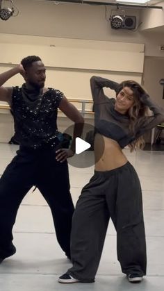 two people dancing in a dance studio with one person wearing black and the other is wearing grey