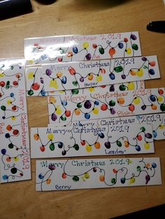 four christmas cards are laid out on a table with pen and paper clips attached to them