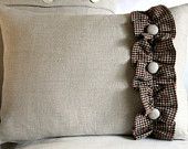 two pillows with ruffles on them sitting next to each other in front of a white couch