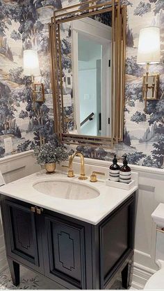 a bathroom with a sink, toilet and wallpapered walls in blue and white