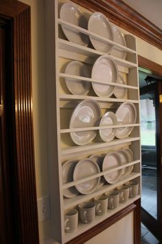 white plates and cups are stacked on a shelf