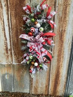 a red and white christmas wreath hanging on the side of a wooden door with ornaments