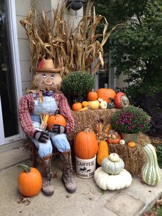 a scarecrow sitting on a porch surrounded by pumpkins and cornstatches