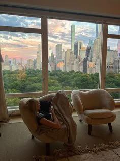 a person sitting in a chair with a laptop on their lap looking out the window