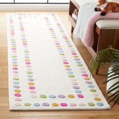 a white rug with multicolored circles on it in a living room next to a window