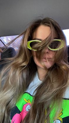 a woman with long hair and yellow sunglasses on her head is sitting in the back seat of a car