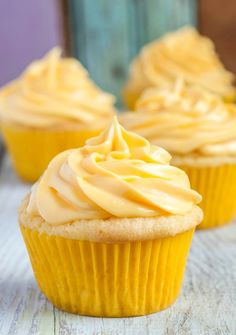 three cupcakes with frosting sitting on a wooden table