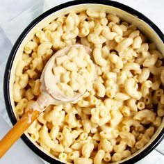 macaroni and cheese is being stirred with a wooden spoon in a black pot