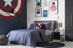 a bedroom with captain america decorations on the wall and bed in the center, along with pictures above it