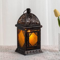 a decorative lantern sitting on top of a table next to a vase with tulips