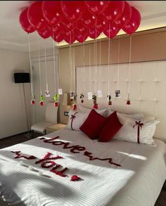 a bed with lots of red balloons hanging from it's headboard and pillows