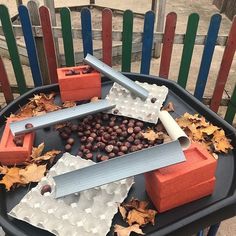 a black trash can filled with lots of different types of objects and leaves on top of it