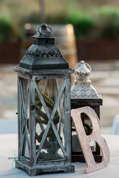 an old fashioned lantern is sitting next to a wooden letter on a table with other items