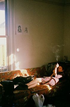 a woman laying on top of a couch in a living room next to a window