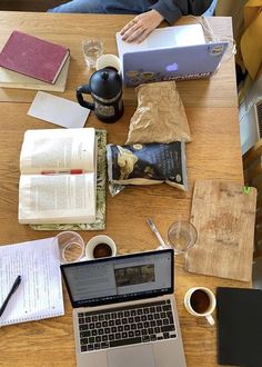 an open laptop computer sitting on top of a wooden table next to a cup of coffee