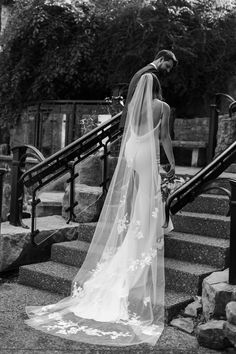 a woman in a wedding dress standing on some stairs with her veil over her head