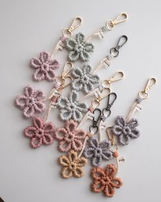 six crochet flower keychains in various colors and sizes on a white surface