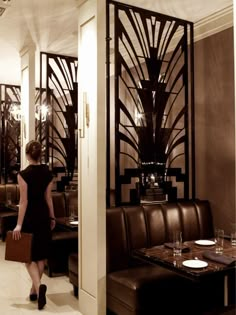 a woman in a black dress is walking into a dining room with tables and chairs