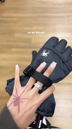 a person with their hand in a glove and spider tattoo on the palm of their left hand