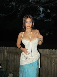 a woman in a white corset and blue skirt is posing for the camera