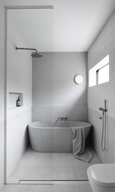 a bathroom with a bathtub, toilet and shower head mounted to the side of the wall