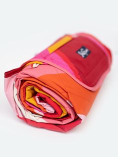 an orange, pink and yellow folded cloth on a white surface