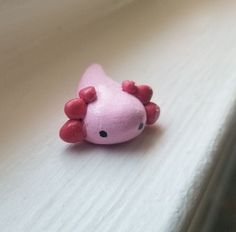 a pink toy with black eyes sitting on a white surface