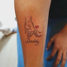 a person with a tattoo on their arm holding the hand of a child's hand