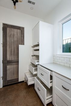 an empty kitchen with white cabinets and drawers